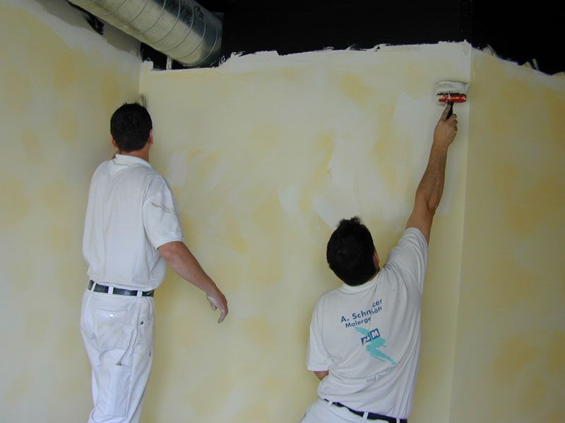Zwei Maler gestalten eine grosse gelbe Wand